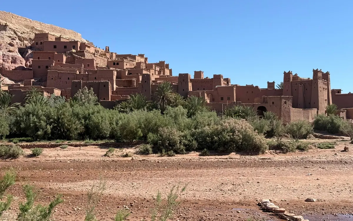 Die Lehmkasbah von Ait Ben Haddou über einem trockenen Flussbett an der Straße nach Süden